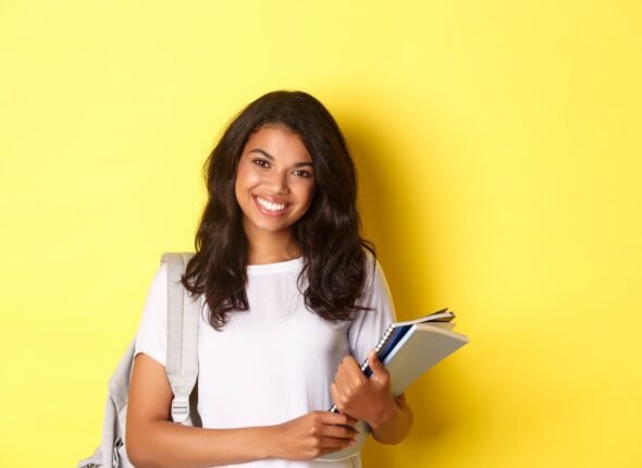 portrait-happy-african-american-female-college-student-holding-notebooks-backpack-smiling-standing-yellow-background_1258-54844
