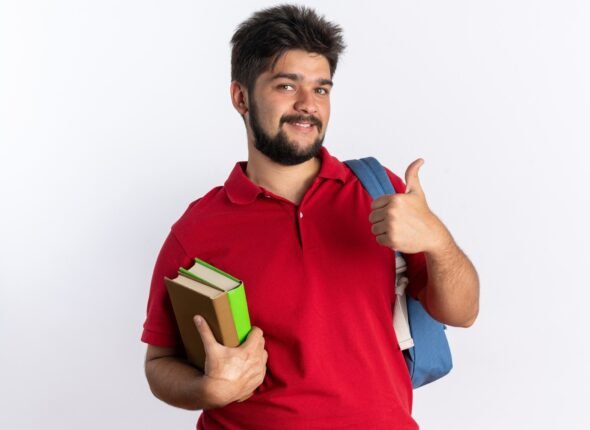young-bearded-student-guy-red-polo-shirt-with-backpack-holding-notebooks-smiling-cheerfully-showing-thumbs-up-standing-white-wall_141793-102001
